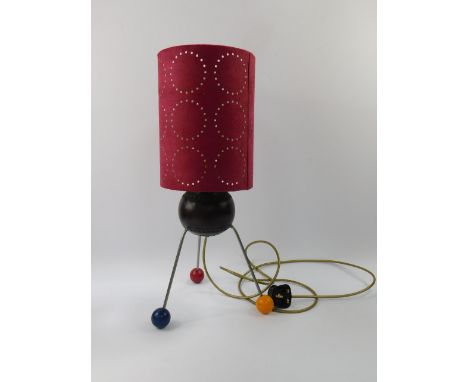An Atomic table lamp, raised on three metal rod and vari-coloured ball feet, with a pierced red shade, 52.5cm high.