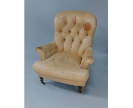 A light tan leather button back armchair, with a loose cushion, raised on turned legs, capped on castors.