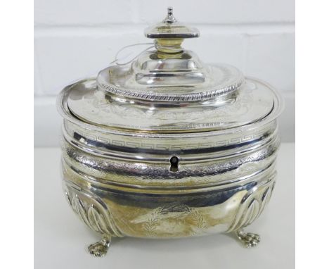 A Georgian silver tea caddy of oval form with Greek Key and foliate bright cut engraving and moulded stiff leaf decoration to