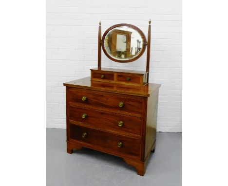 An Edwardian mahogany and inlaid dressing table with oval swing mirror above a pair of short drawers and three long drawers o