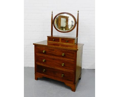 An Edwardian mahogany and inlaid dressing table with oval swing mirror above a pair of short drawers and three long drawers o