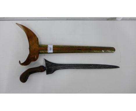 A Kris with watered steel blade and carved wooden hilt, contained within its typical brass mounted and wooden scabbard, blade