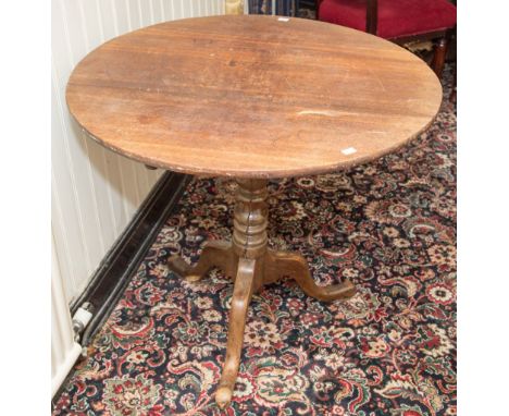 An early 19th century oak tripod table, raised on a baluster and ring turned column