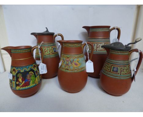 A graduated set of Prattware terracotta jugs with Greek key and mask design, together with two other jugs with different poly