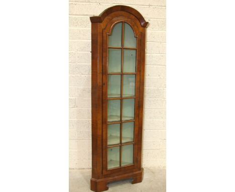 A walnut narrow corner display cabinet, the arched cornice above a single astragal-glazed door, on bracket feet, 54cm wide, 1