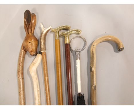 A collection of various walking sticks to include a long walking stick with good carved rabbits head knop, two brass ended Su