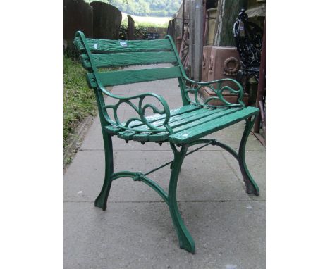 A garden chair with slatted seat and back raised on a pair of decorative cast aluminium ends and all over green painted finis