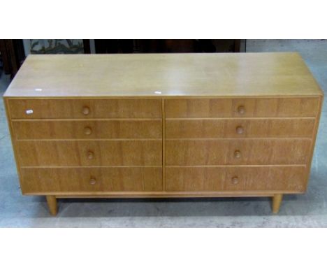 A Meredew light oak veneered low bedroom chest fitted with a side by side arrangement of eight graduated drawers raised on si