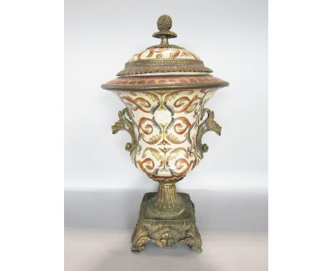 Eastern porcelain and cast metal lidded urn, the lid with fruiting finial and darted borders over a baluster base, gilded and