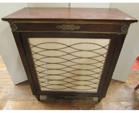 A small Regency style side cupboard, the single door with pleated panel detail and brass grill finish, raised on turned suppo