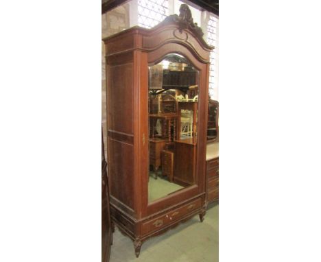 An oak hanging cupboard enclosed by a large mirror panelled door with bevelled edge plate over a single frieze drawer beneath