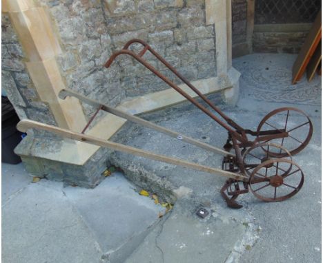 A vintage push hoe with two iron spoke wheels and weathered timber shafts, together with one other (2)