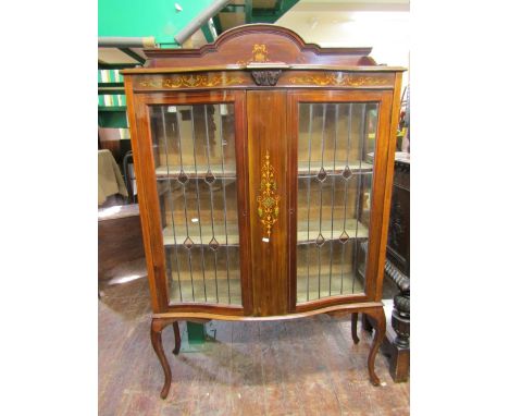 An Edwardian china display cabinet of serpentine form, the central marquetry panel flanked by leaded light doors raised on sh