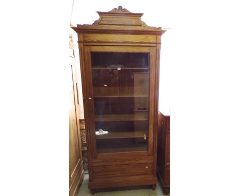 A stripped and waxed pitch pine display cabinet, the plate glass door over a single frieze drawer with four adjustable shelve