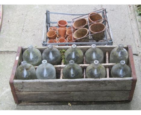 A vintage crate containing twelve glass bottles together with a further galvanized crate and a small collection of clay flowe