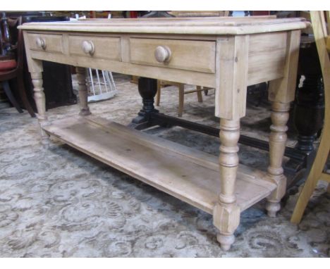 A 19th century stripped and waxed pine dresser base enclosed by three shallow drawers over an open pot cupboard with turned s