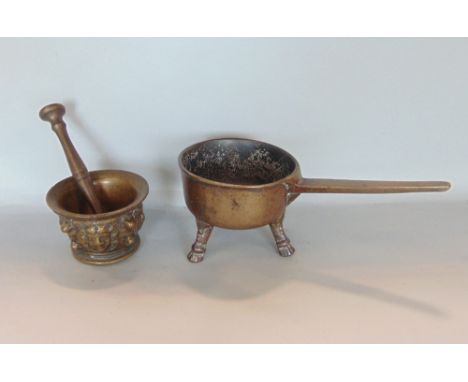 Antique cast brass pestle and mortar, decorated with various masks, together with a further cast bronze skillet with three ho