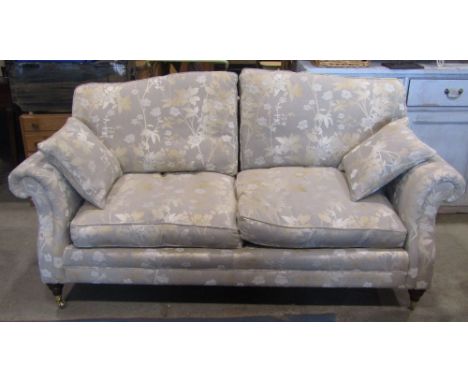 A good quality contemporary two seat sofa retailed by John Lewis with scrolled arms and floral upholstered finish raised on t