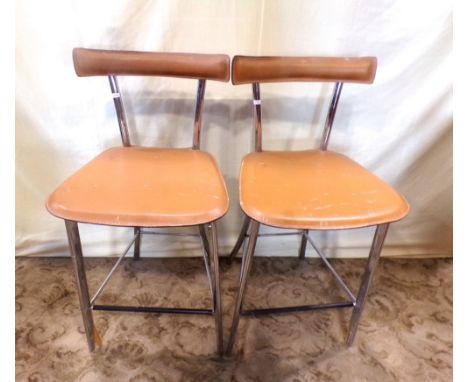 A pair of Italian high bar stools with chrome frames and light tan coloured stitched seats and back rails/pads 