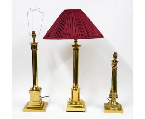 THREE POLISHED GILT-METAL COLUMN TABLE LAMPS (3)One with weighted base and lotus leaf ornament, 59cm including shade; another