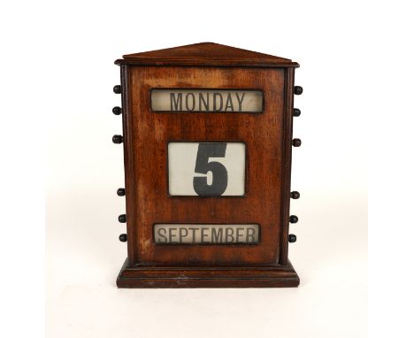 A MAHOGANY PERPETUAL DESK CALENDAREarly 20th Century 
Of architectural form, glazed apertures and canvas rollers, 33cm highCo
