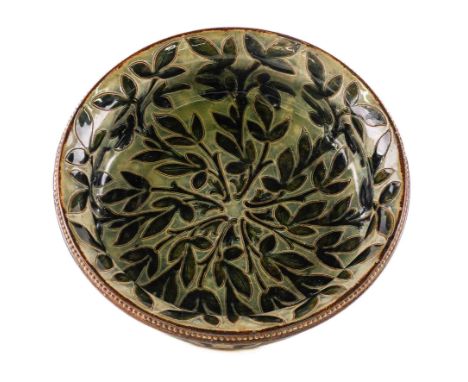 A DOULTON STONEWARE FOOTED BOWLDated 1885Decorated by Frank Butler, the interior incised with dark green leaves against a mot