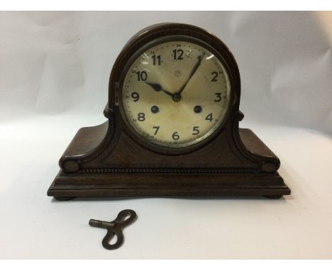 An oak metal clock with a silver dial and Arabic numerals.