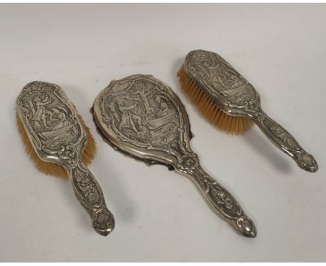 Silver hand mirror, embossed with a couple in a landscape with trees, and matching hair brushes, by Samuel Jacob London 1902.