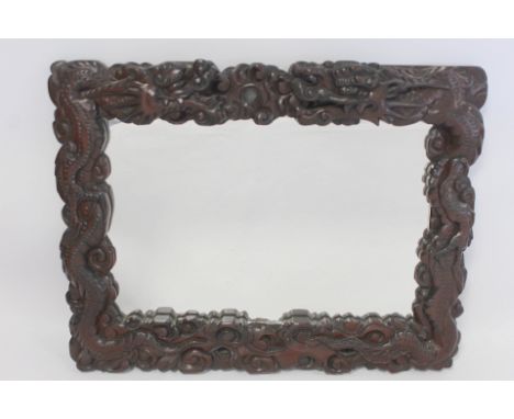 Late 19th or early 20th century Chinese carved hardwood wall mirror, the frame in the form of two scrolling dragons amongst c