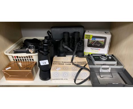 A Shelf of cameras and binoculars to include Cobra Model 750 binoculars, Tom tom sat nav, Polaroid Automatic land camera and 