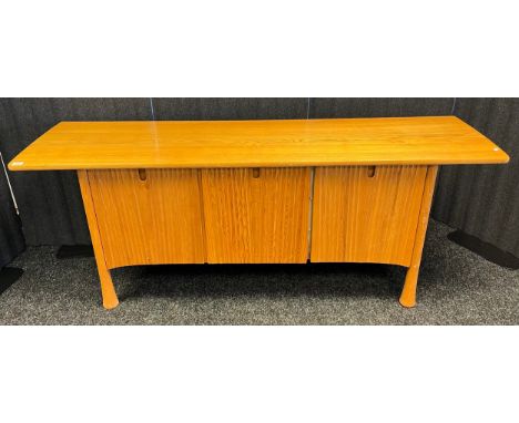 An unusual mid century style Ercol blonde/ golden oak sideboard. Bevel sides and door design. [Missing facer] [73x194x53cm] 