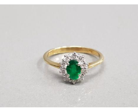 18CT YELLOW GOLD EMERALD AND DIAMOND CLUSTER RING COMPRISING OF A SINGLE OVAL EMERALD COMPLETE WITH A CLUSTER OF ROUND CUT DI