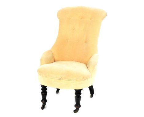 A Victorian ebonised spoon back nursing chair, with button back peach upholstery, overstuffed seat, raised on turned legs, on