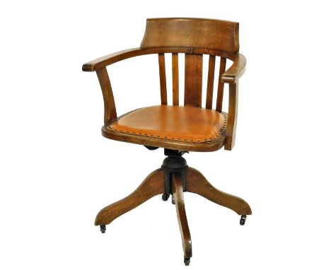 An early 20thC oak captain's chair, with button fringe leatherette seat, raised on a swivel base on castors, 61.5cm wide.