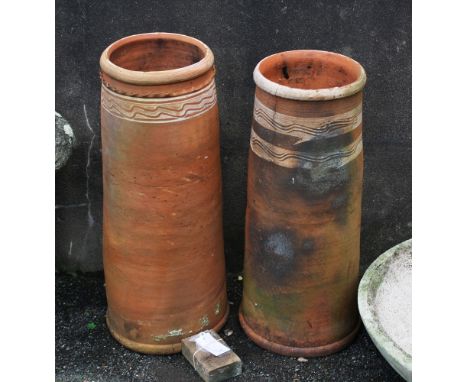 Two tall terracotta chimney pots, both with painted white wave design, the taller one with applied piecrust surround below ri