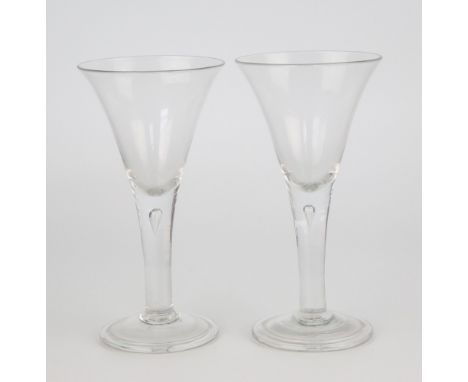 A pair of Georgian wine goblets, circa 1760, large drawn trumpet form bowls on stems with tear drops tapering into folded fee