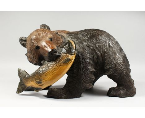 A LARGE JAPANESE KIBORI KUBA CARVED WOODEN FIGURE OF A BEAR, the bear in striding position with a fish in its mouth, 27cm hig