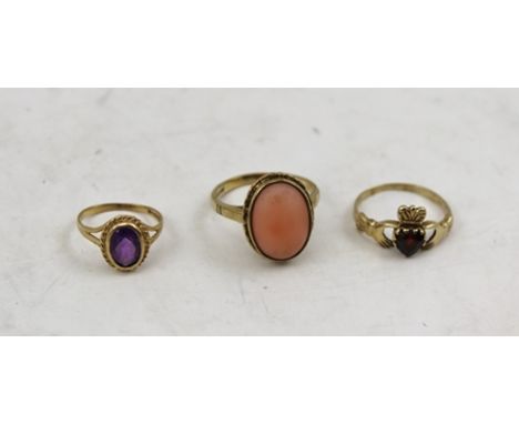 THREE LADY'S RINGS comprising; a 9ct gold lady's ring inset with oval coral, ring size N, a garnet "heart in hands" ring and 