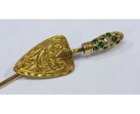 An early 20th century unmarked gold brooch pin, the finial modeled as a trowel or cake slice, the handle set with emeralds an