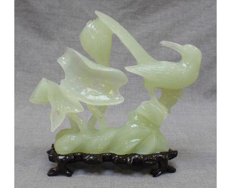 A 20th Century jade carved figure of a bird amidst flowers, on a naturalistic shaped base. 20cm high.