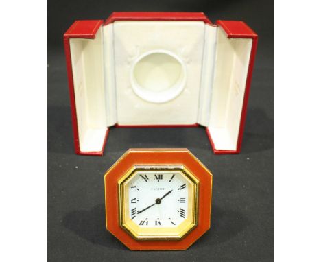 A Must de Cartier octagonal travel alarm clock, the white dial with Roman Numeral's depicting hours, surrounded by a red lacq