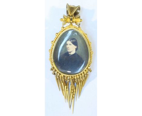 A 15 carat gold fringed portrait pendant set with a pear shaped garnet, circa 1860