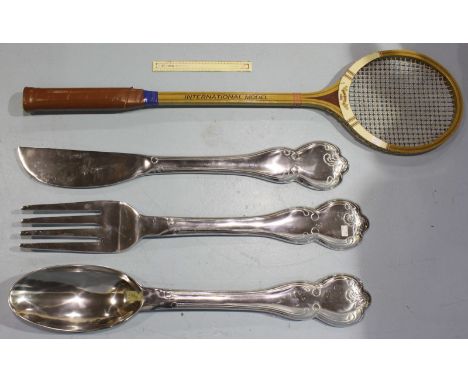 An oversize "Maxiply" wooden tennis racket, 138cm long, together with an oversize white metal knife, fork and spoon, 100cm  e