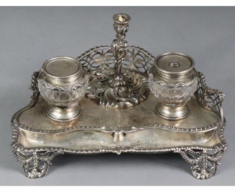 A Victorian silver inkstand of serpentine shape, with pierced gallery, fitted two glass inkwells with silver mounts &amp; rem