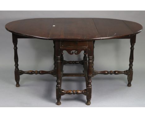 An antique oak oval gate-leg dining table fitted end drawer, &amp; on baluster-turned legs &amp; turned feet with turned stre