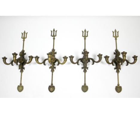 A SET OF FOUR&nbsp;EARLY 20th CENTURY GILT BRASS WALL LIGHTS, each with 'trident-fork' backs, &amp; three scroll arms, a scal