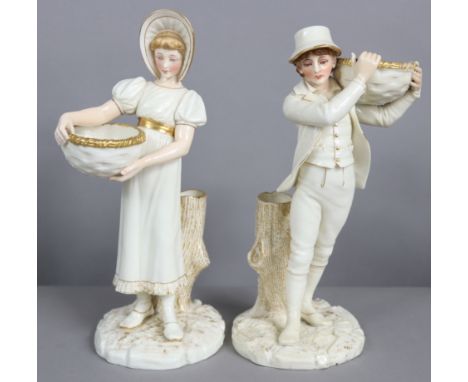 A pair of Royal Worcester porcelain ivory &amp; gilt standing male &amp; female figures, the faces &amp; arms painted in colo