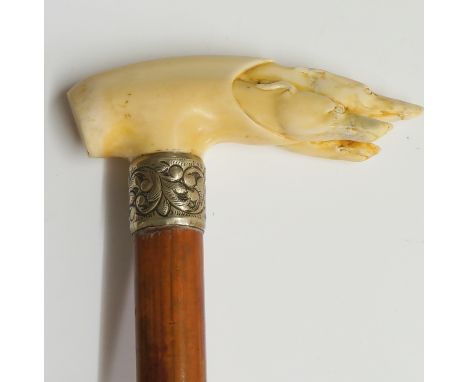 A 19th Century walking stick, the handle carved with three greyhound's heads, foliate engraved white metal collar, bamboo sha