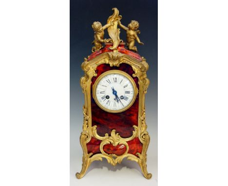 A French ormolu mantel clock, the case veneered overall with red tortoiseshell, the top with pair of winged amorini around a 
