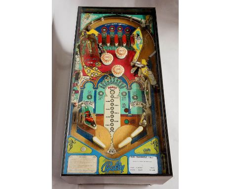 A Bally Aladdin's Alley pinball machine converted to a coffee table with brushed stainless steel surround, legs and under tie